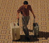 Man rolling a luxury trolley bag and vintage trunk luggage suitcase on a tiled floor. Best spinner suitcase for travel.