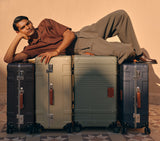 Man posing with a luxury trolley bag set. These vintage trunk wingman luggage pieces are the best spinner suitcases for travel.